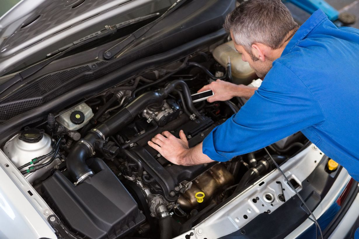 Mechanic inspecting a car engine in an open hood.
