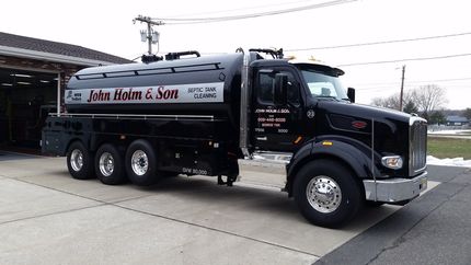 Black fuel tanker truck with "Luke Haines & Son" logo parked in front of a building.