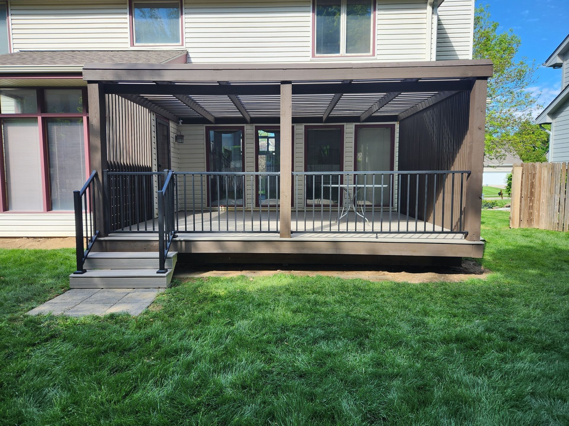 A deck with a pergola on top of it in the backyard of a house.