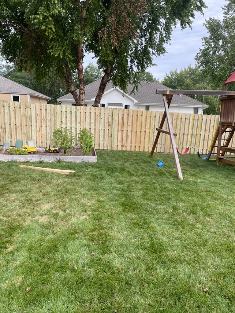 A backyard with a wooden fence and a swing set.