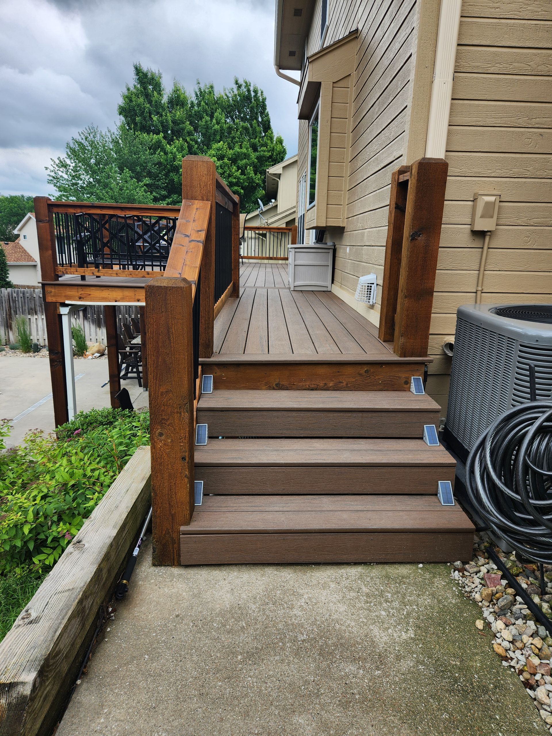 A wooden deck with stairs leading up to it next to a house.
