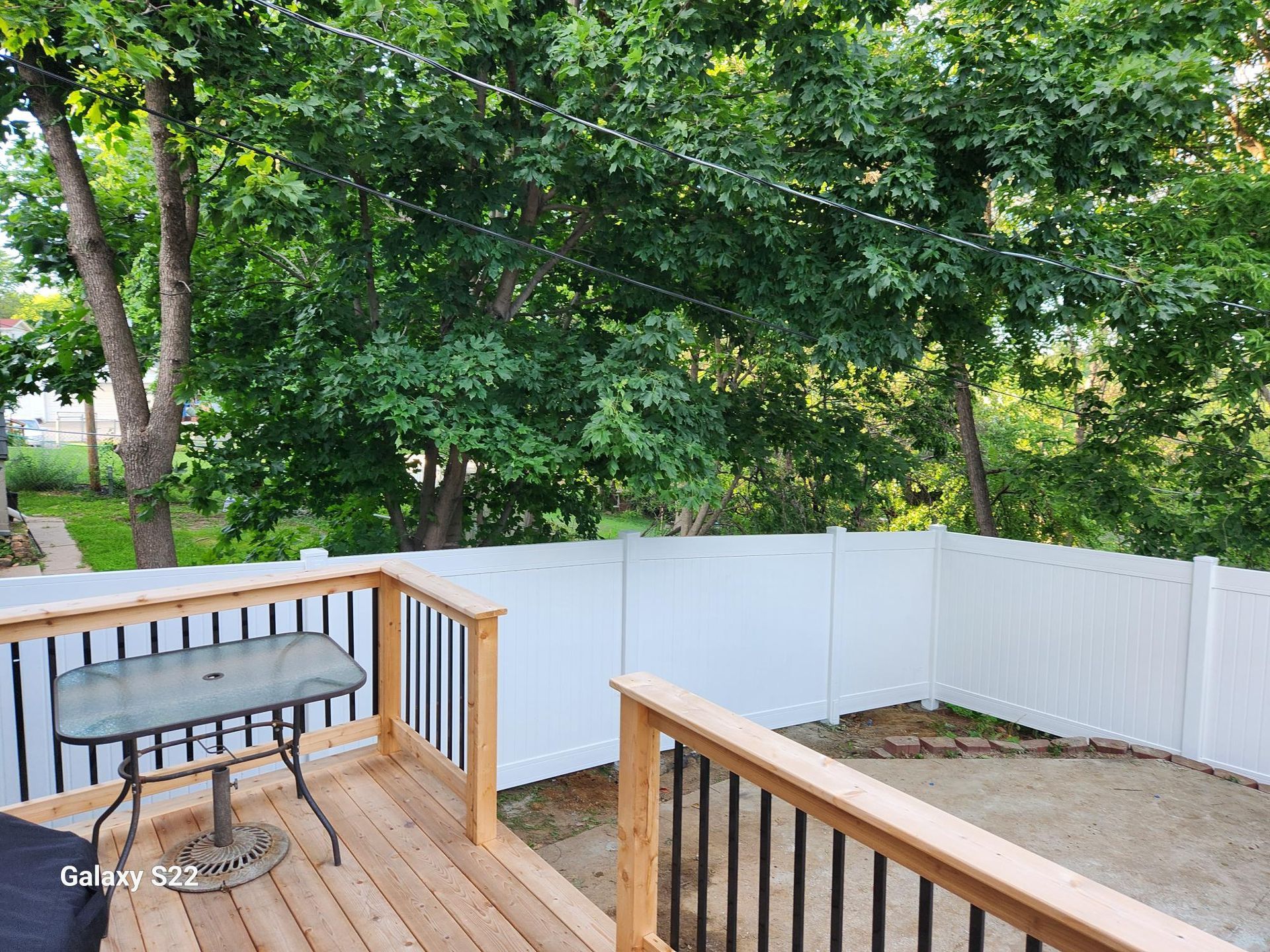 A wooden deck with a table and chairs and a white fence.
