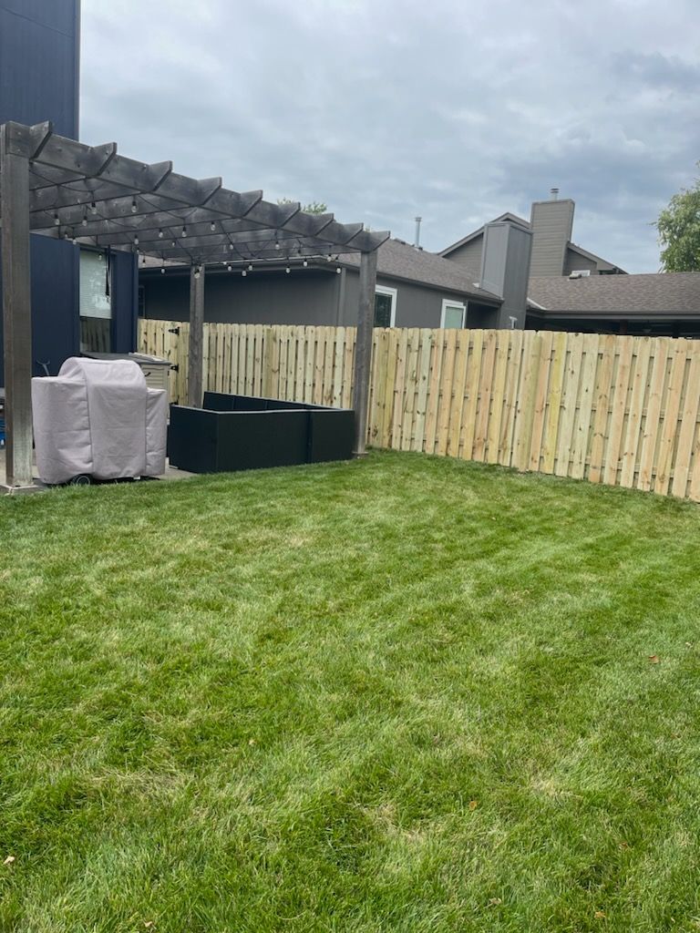A backyard with a wooden fence and a pergola.