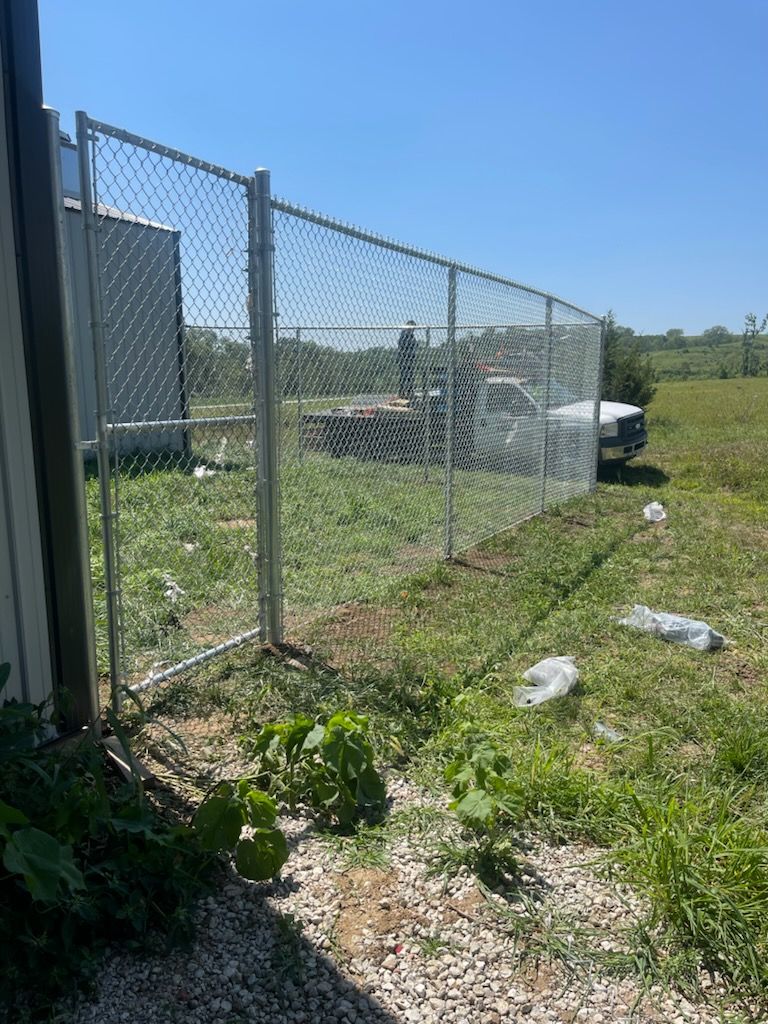 A chain link fence is surrounding a grassy field.
