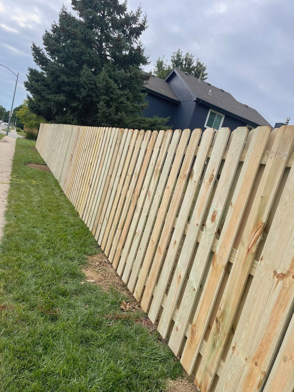 A wooden fence is sitting in the grass next to a house.