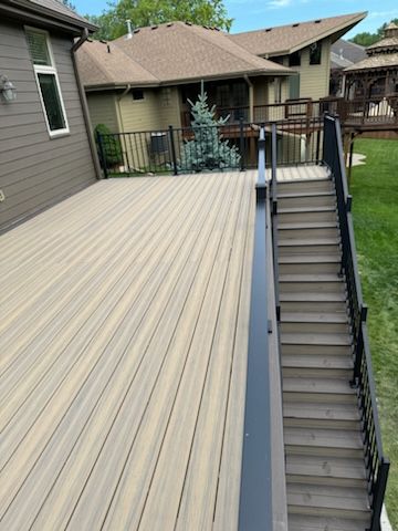a wooden deck with stairs leading up to it and a house in the background