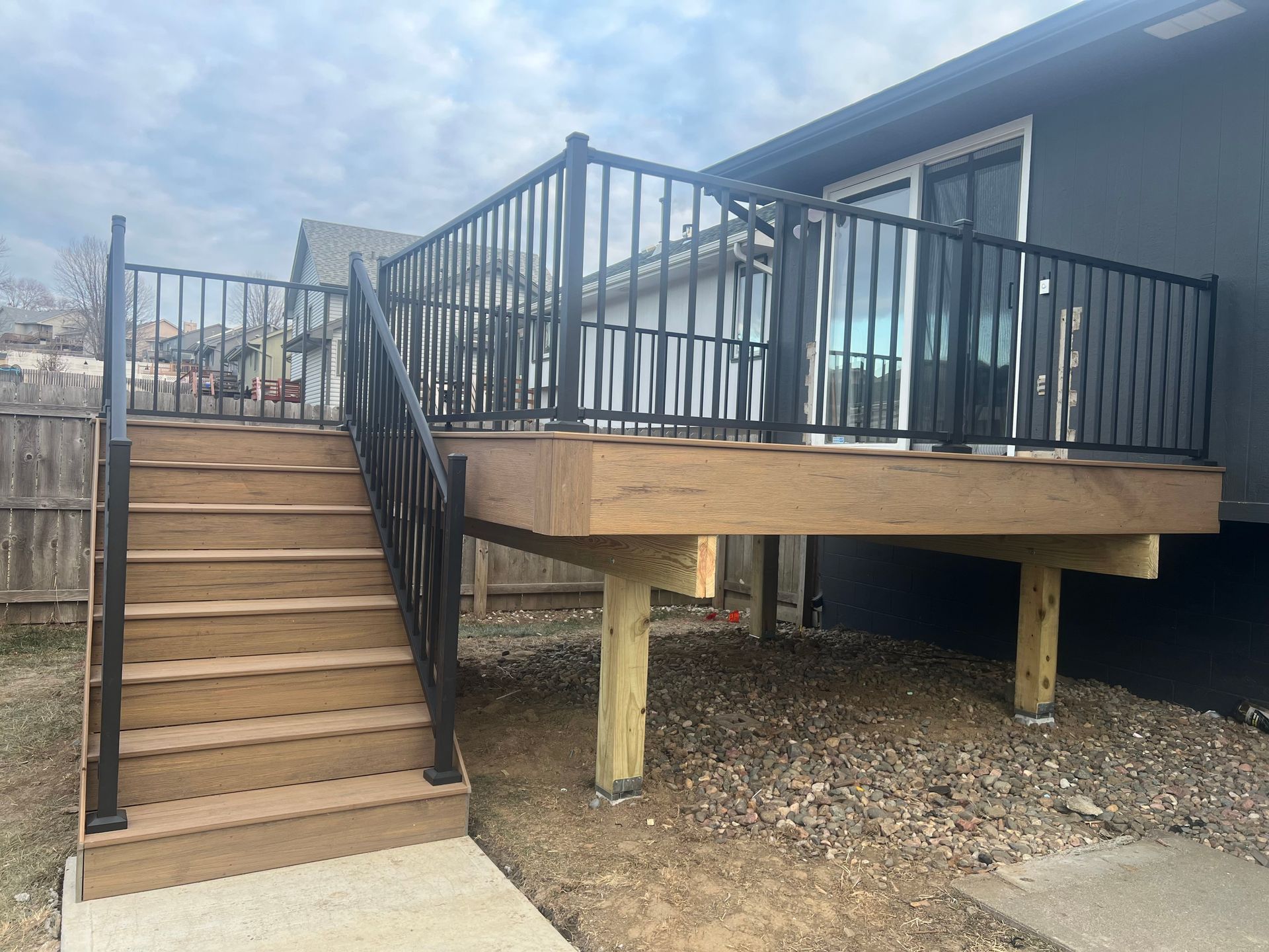 a wooden deck with stairs leading up to it in front of a house