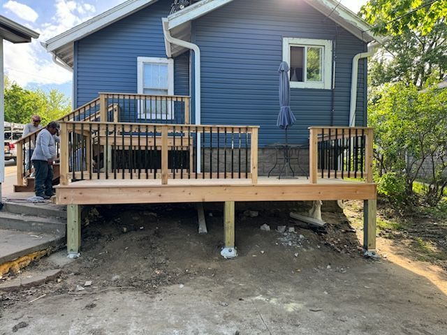 A wooden deck is being built in front of a blue house.