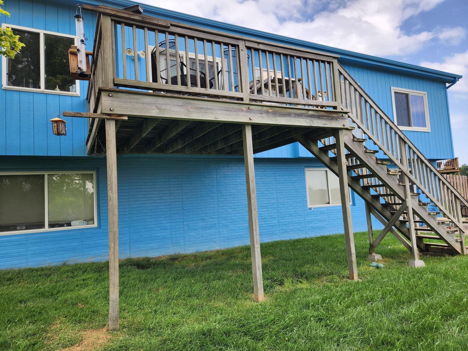 A blue house with a wooden deck and stairs