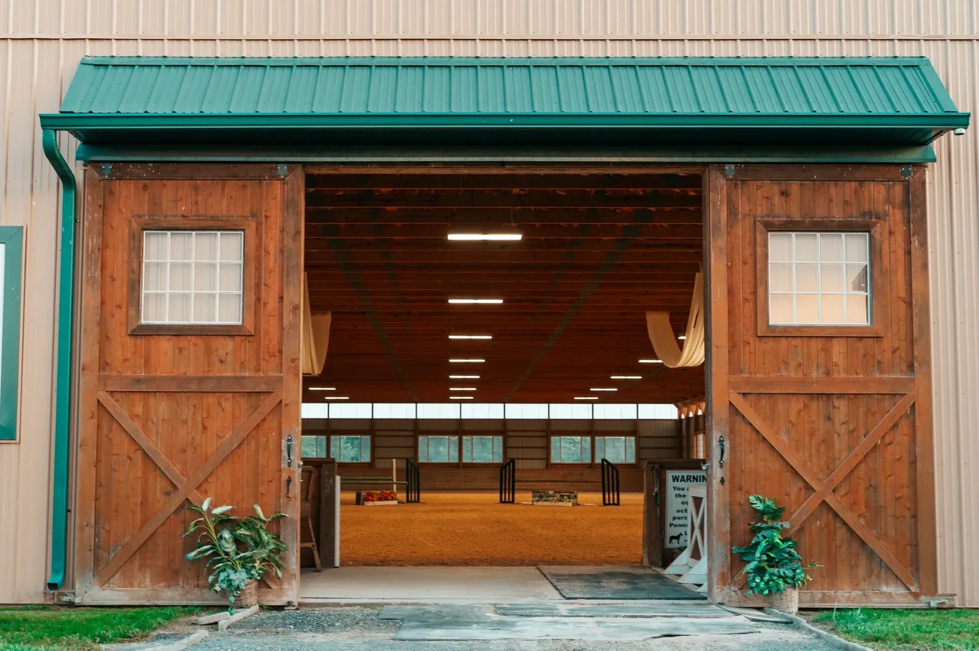 Large wooden barn doors open to an indoor arena.