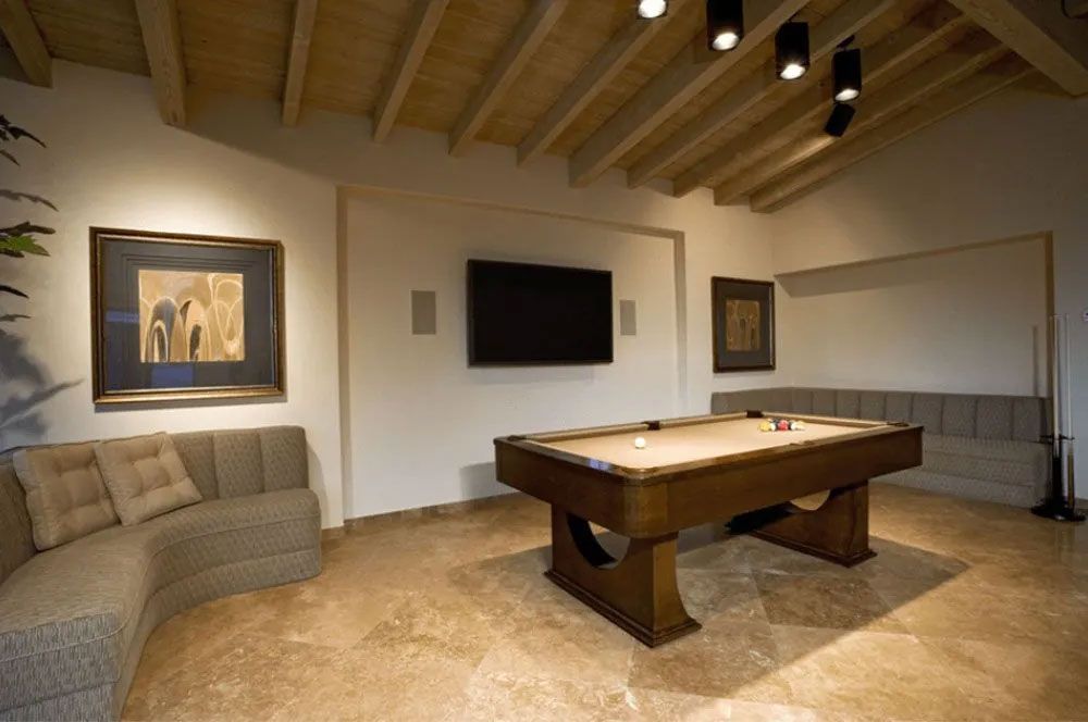 Pool room with a pool table, sectional sofa, artwork, TV, and track lighting.