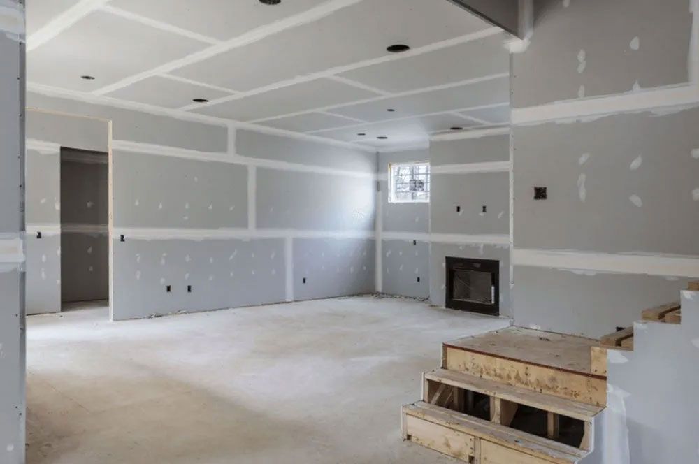 Unfinished interior with drywall, a fireplace, stairs, and recessed lighting.