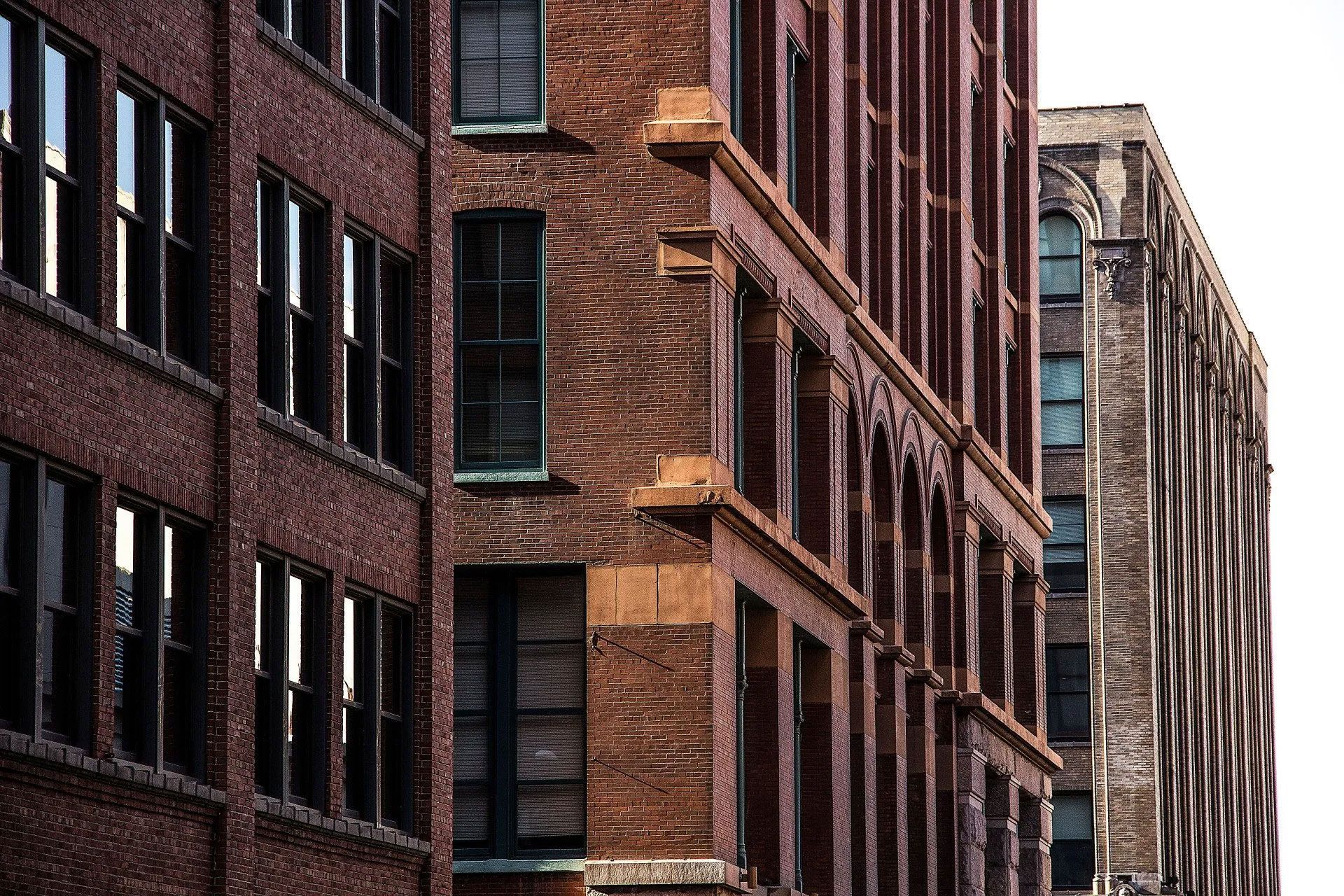 Brick buildings with windows, in an urban setting, showing the corner of one building.