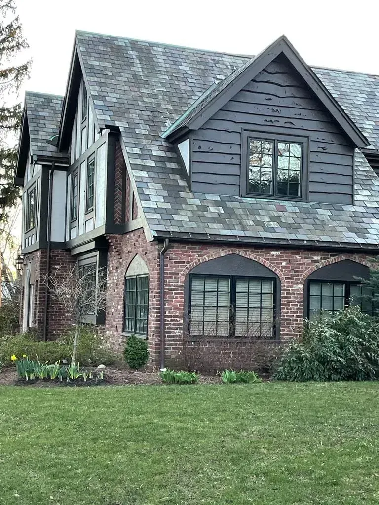 Brick house with dark roof, brown trim, and arched windows.