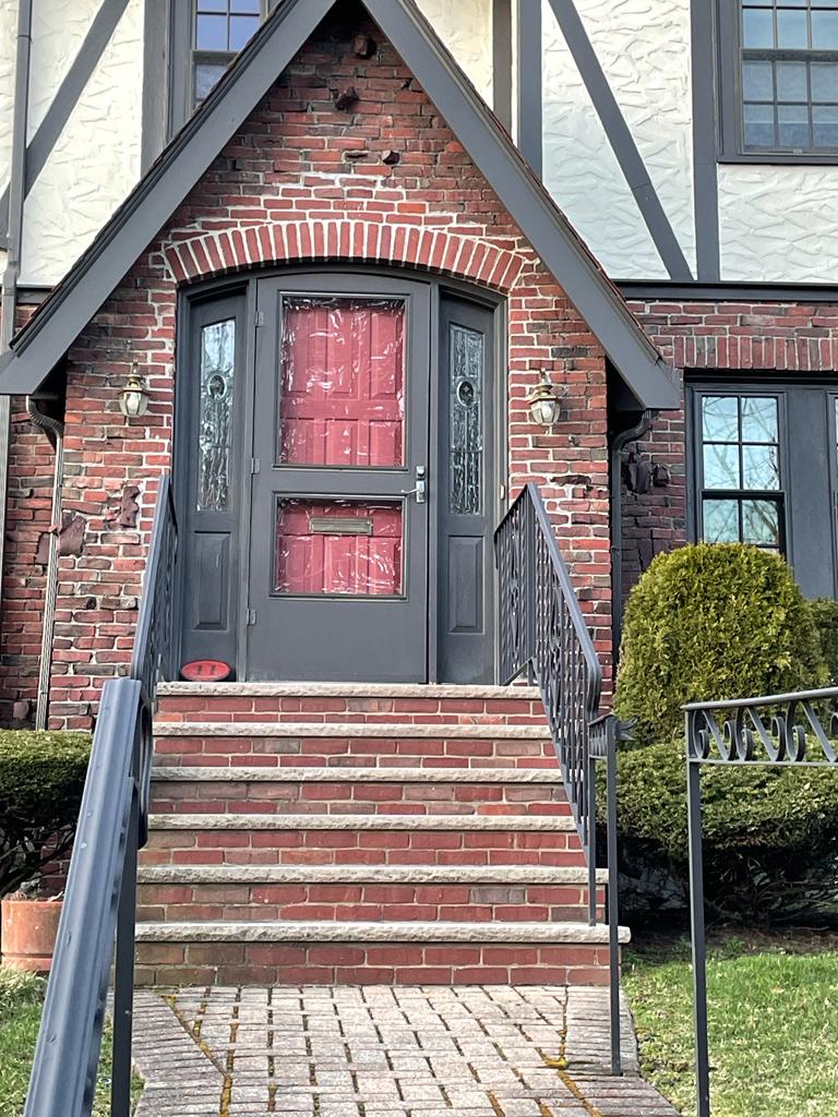 Brick house entrance with steps, gray door frame, red door.