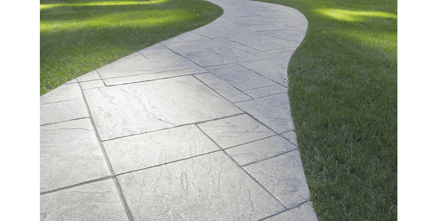 A concrete walkway going through a lush green field.