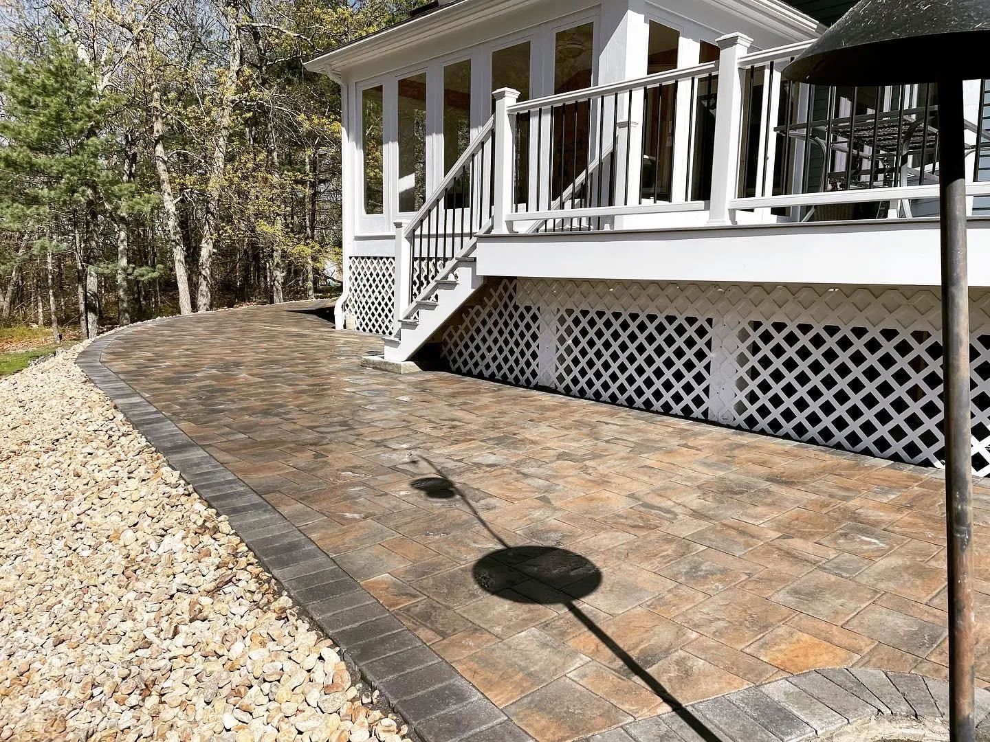 Brick patio with a white porch, steps, and gravel border.