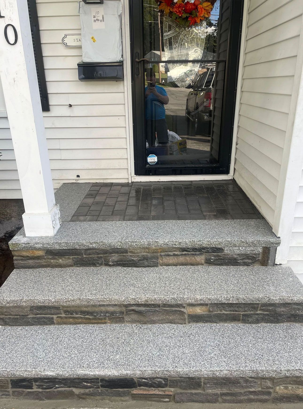 Steps leading to a front door. Granite steps lead to a small paved porch and the front door.