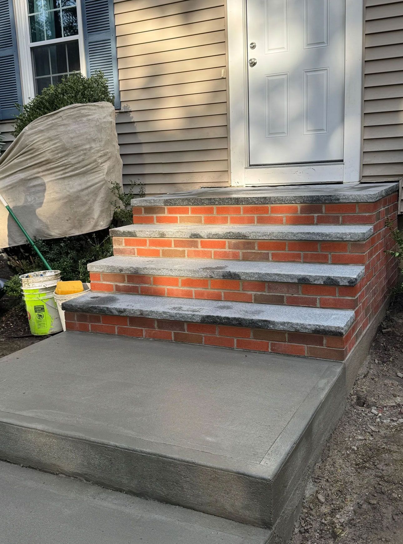 Brick steps with concrete landing leading to a white door.