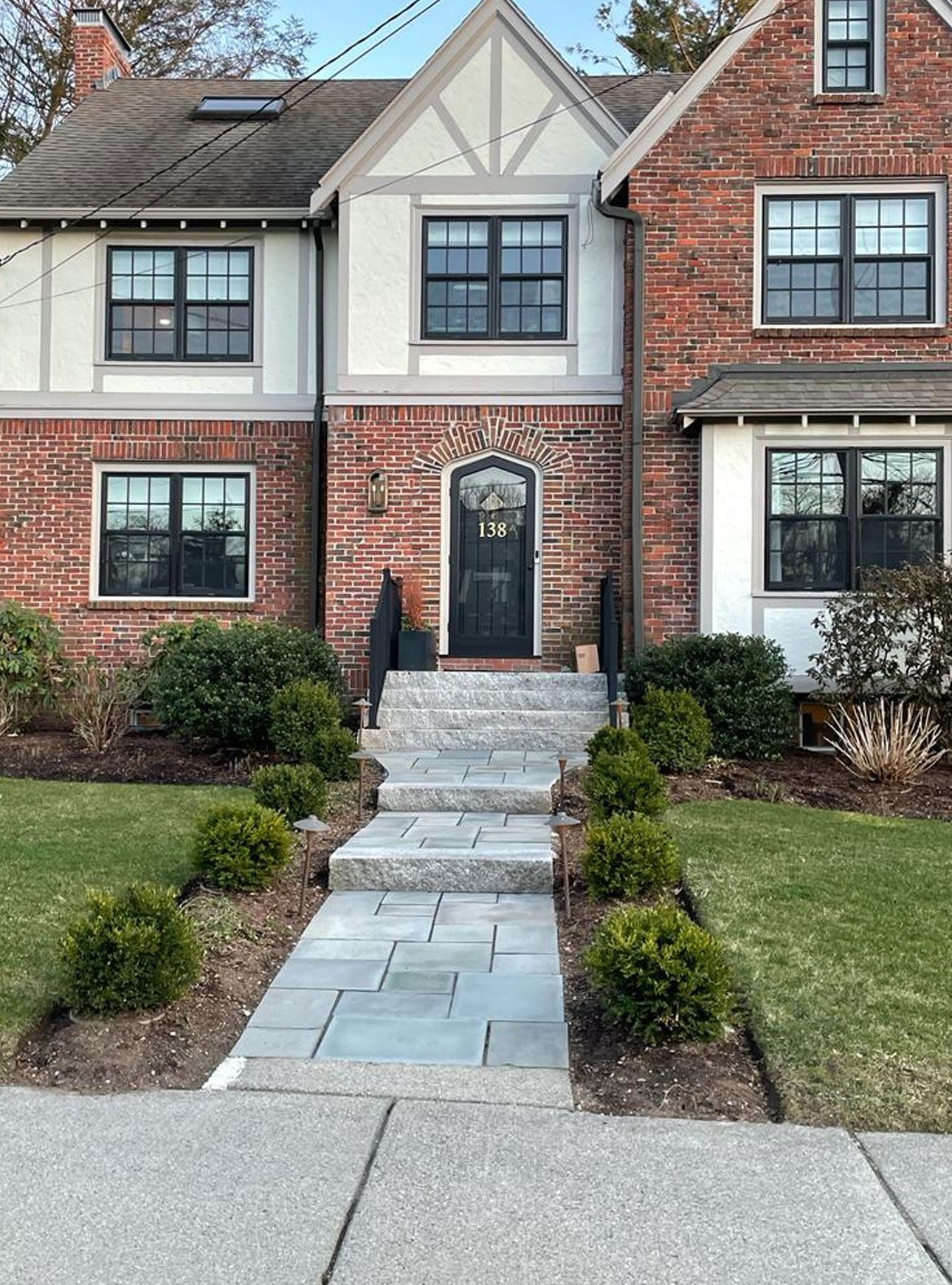 Brick Tudor home with stone walkway and landscaping.