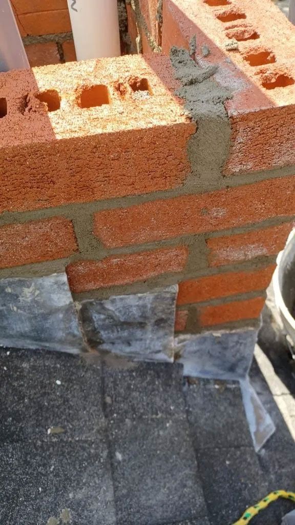Brick construction, red bricks layered with mortar, gray lead flashing at the base.