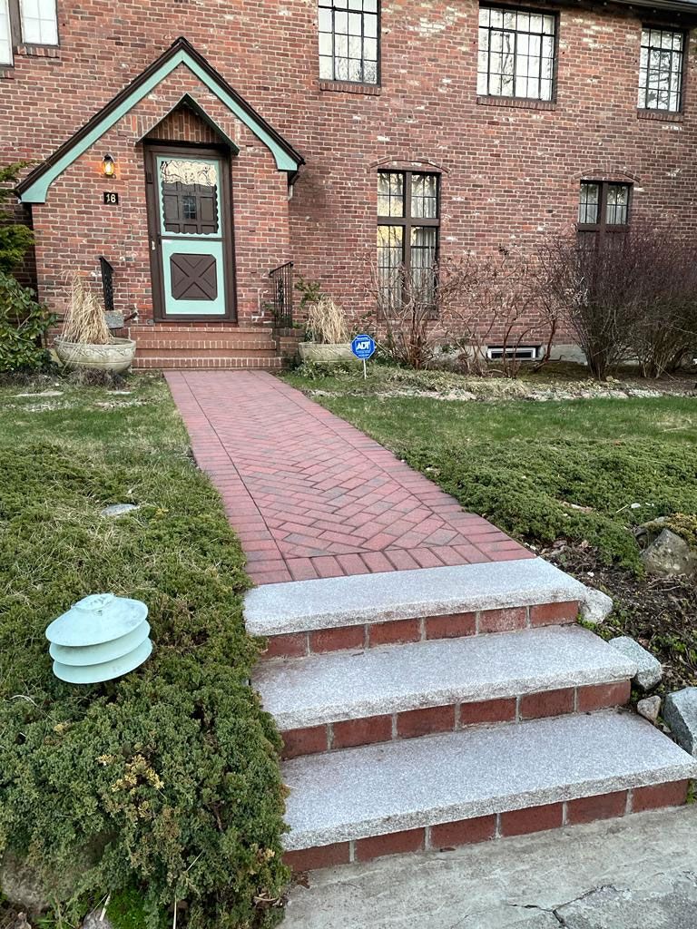Brick building with red brick walkway leading to a front door with steps.