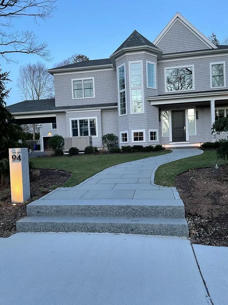Gray two-story house with a curved walkway, steps, and a mailbox, outdoors.