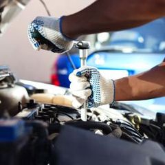 A man is working on the engine of a car with a wrench.