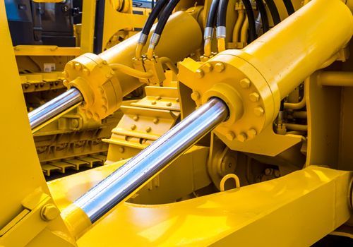 A close up of a yellow hydraulic cylinder on a bulldozer.