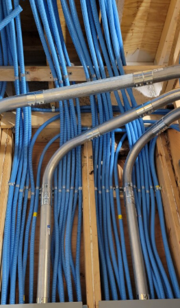 Blue electrical conduit pipes installed in a wood frame ceiling.