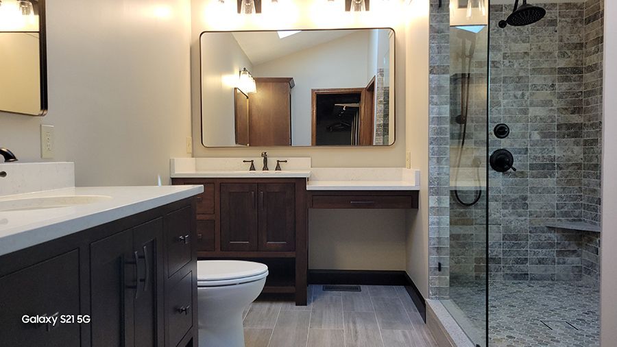 Bathroom with a dark wood vanity, white countertop, and tiled shower.
