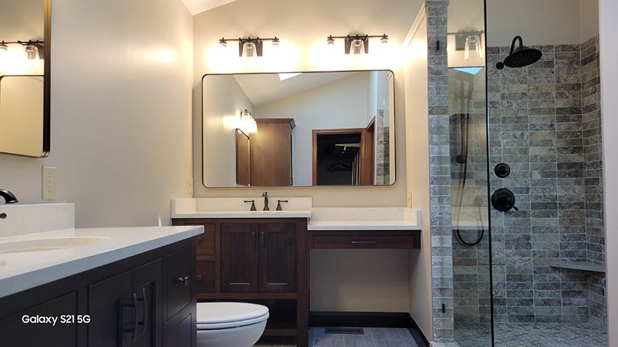 Bathroom with dark wood vanity, large mirror, and glass shower.