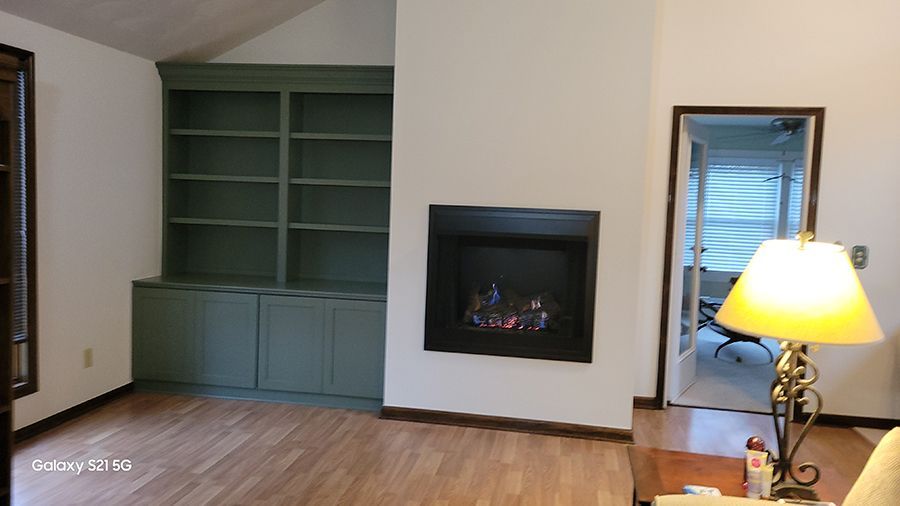 Living room with green built-in shelves, a fireplace, and a doorway to another room.