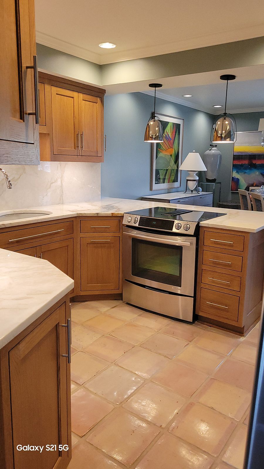 Kitchen with wood cabinets, stainless steel appliances, and terracotta tile floors.