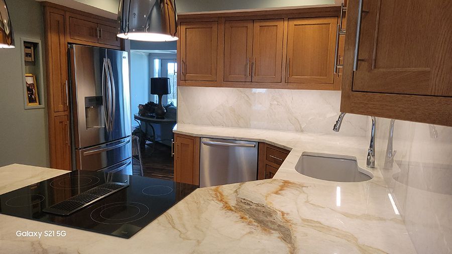 Kitchen with light-colored countertops, stainless steel appliances, and brown wood cabinets.