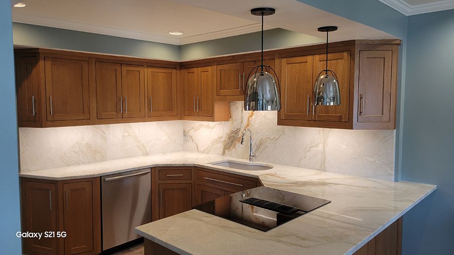 Kitchen with light wood cabinets, white countertops, and stainless steel appliances.