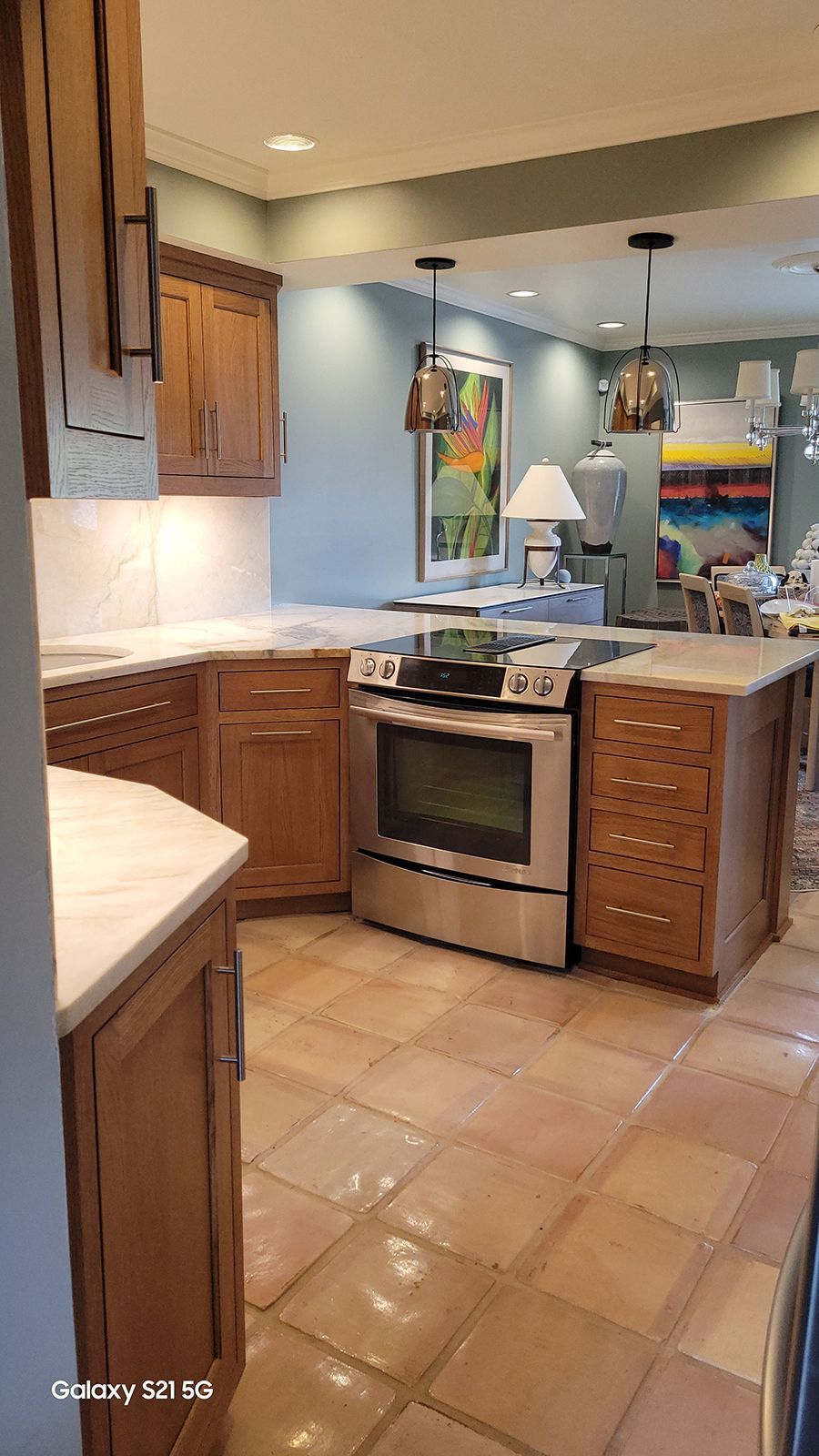 Kitchen with light wood cabinets, stainless steel oven, and tile flooring.