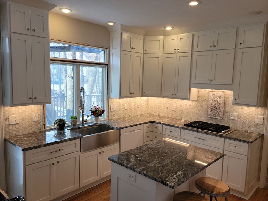 White kitchen with granite countertops, stainless steel sink, and island.