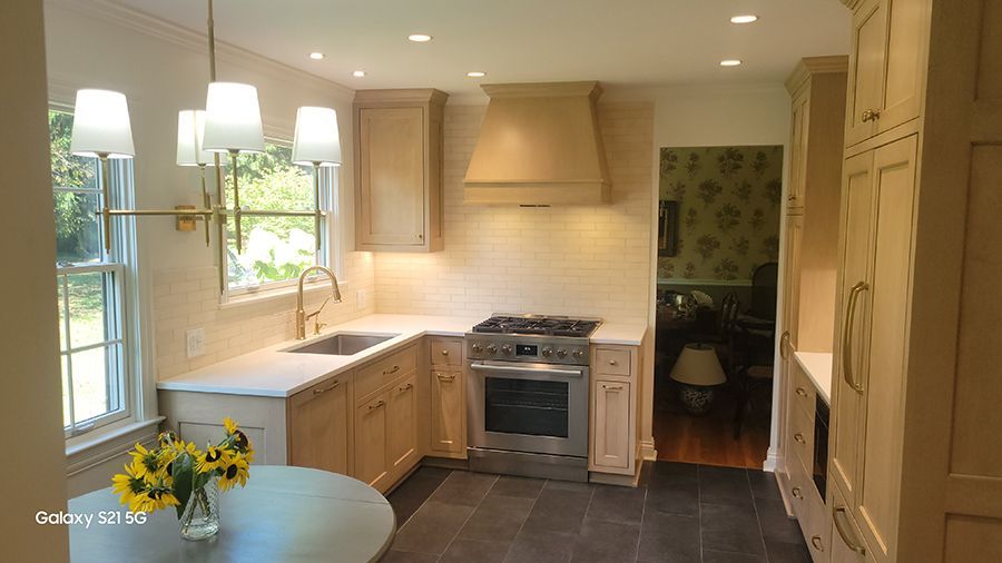 Kitchen with light wood cabinets, stainless steel appliances, and a round table.
