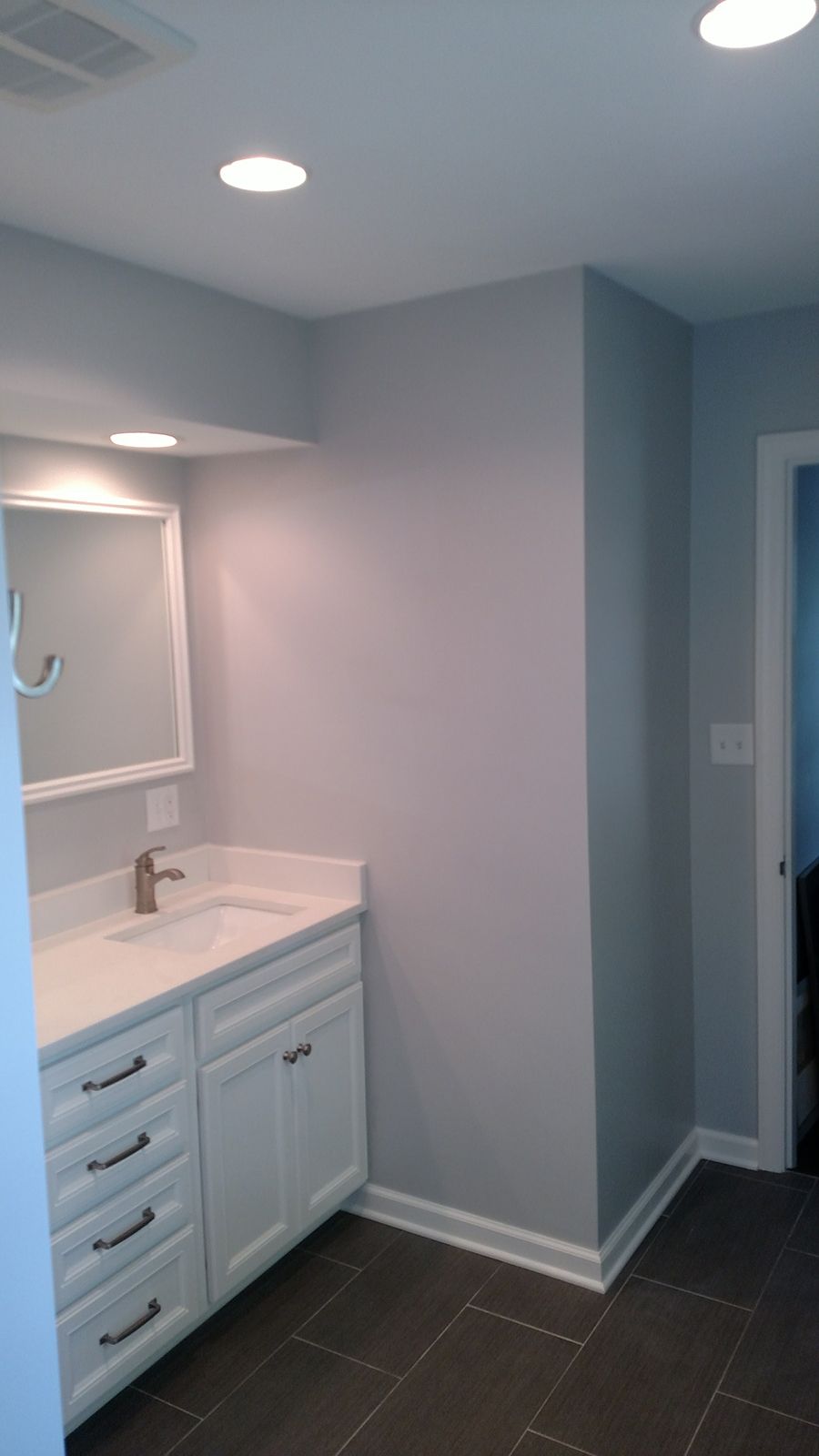 Bathroom with white vanity, gray walls, and dark tiled floor.