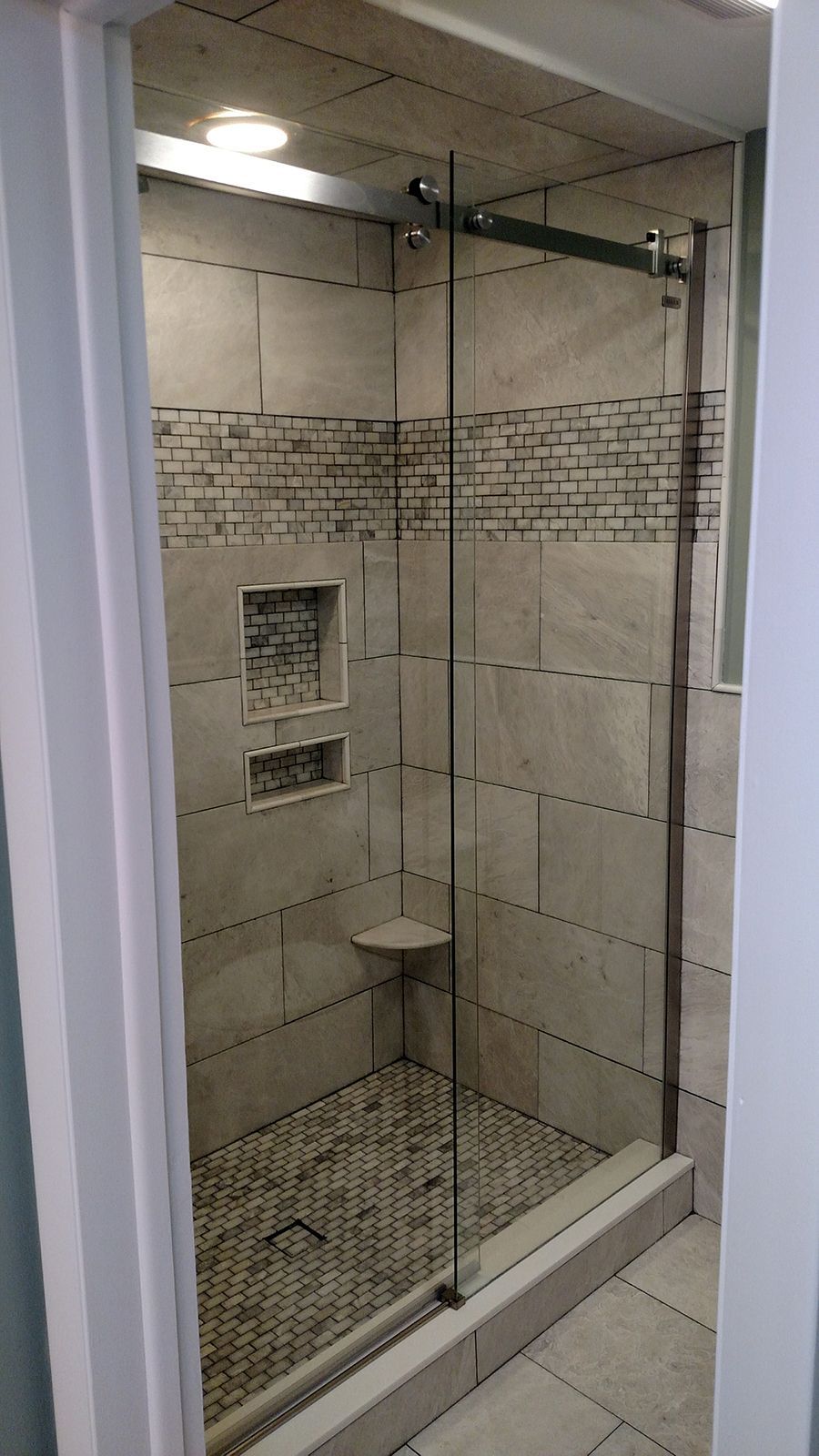 Shower with glass door, stone floor, and tile walls; pebble-style floor.