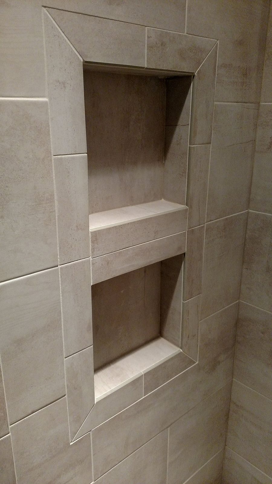 Recessed tiled shower shelf with two shelves. Beige tile surrounds the opening.