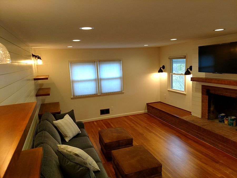 Living room with a gray couch, wooden floor, fireplace, and two windows.