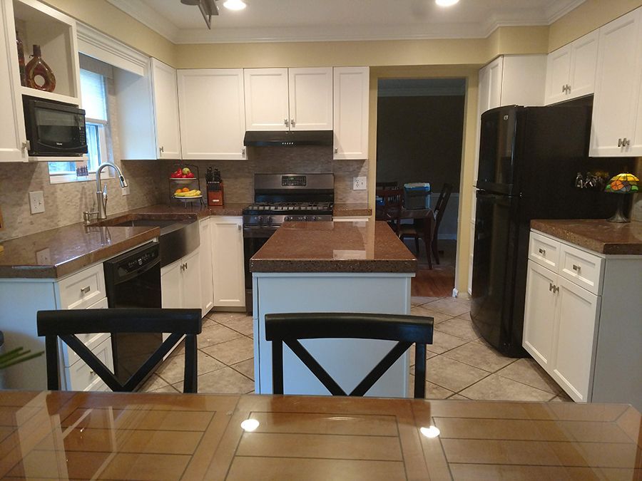 A kitchen with white cabinets, brown countertops, and a black refrigerator and range.