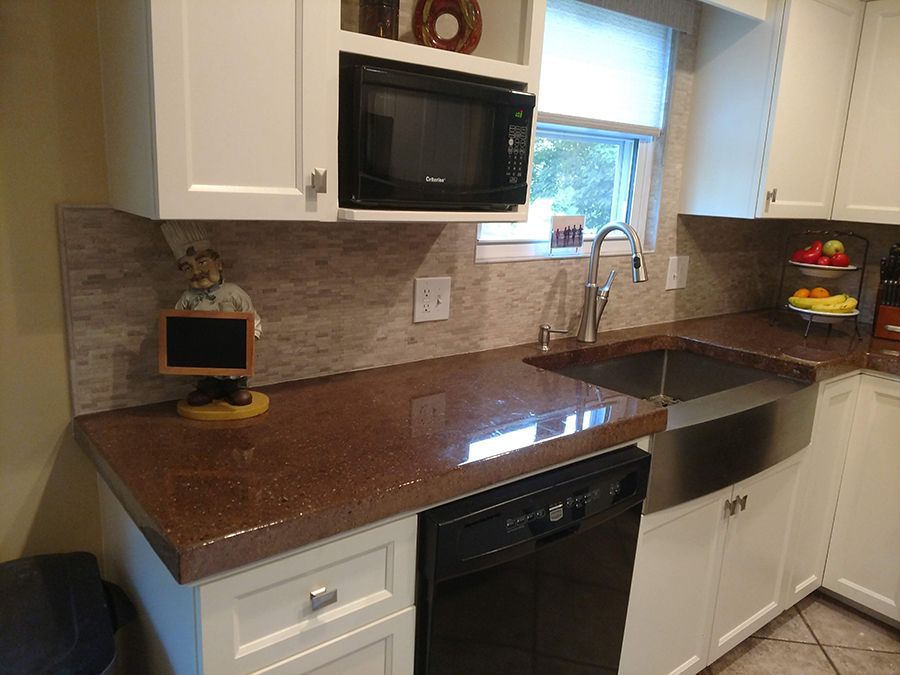 Kitchen with brown countertop, white cabinets, stainless steel sink, and a microwave.