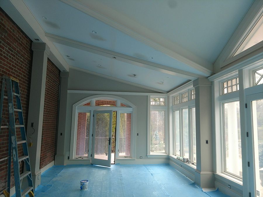 Interior of a room under construction with exposed brick wall, windows, and a ladder.