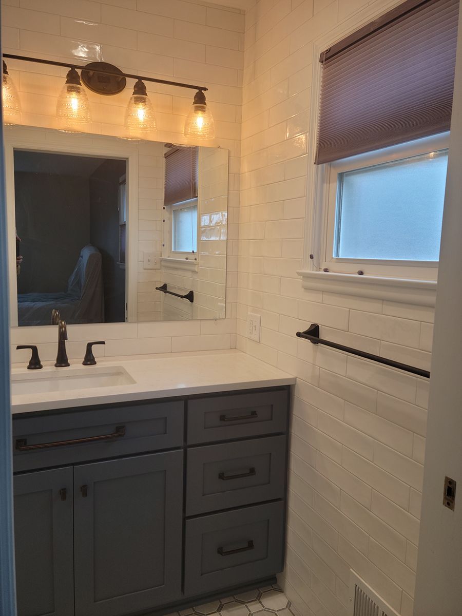 Bathroom with gray vanity, white subway tile walls, and a window with a shade.