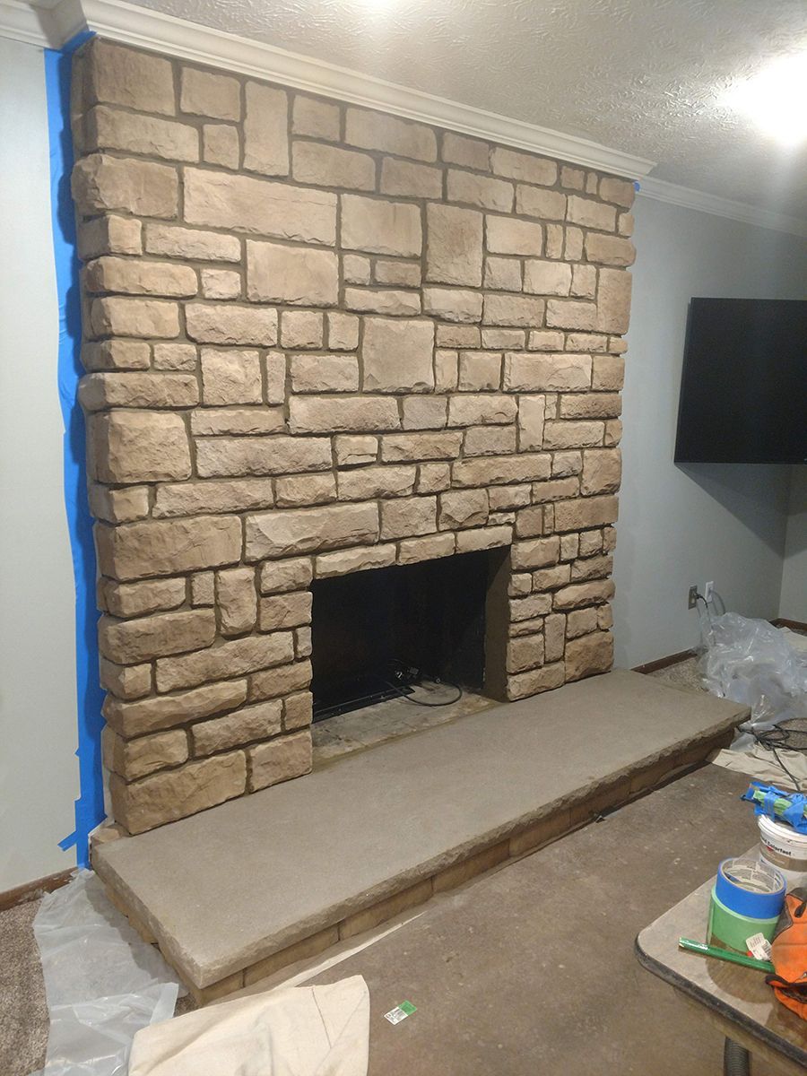 Stone fireplace with gray hearth; blue tape on wall.