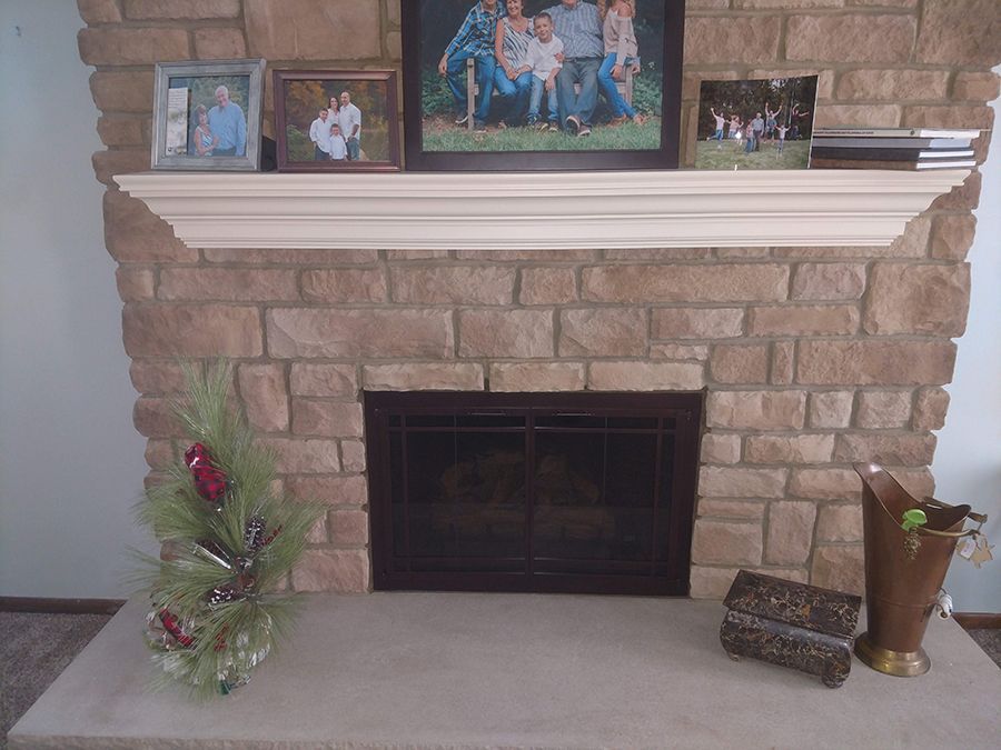 Stone fireplace with a wooden mantle and family photos. Decorations on the hearth.
