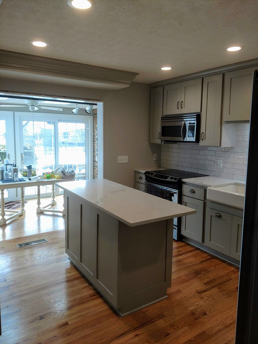 Gray kitchen with island, cabinets, and appliances; a window and wood floors.